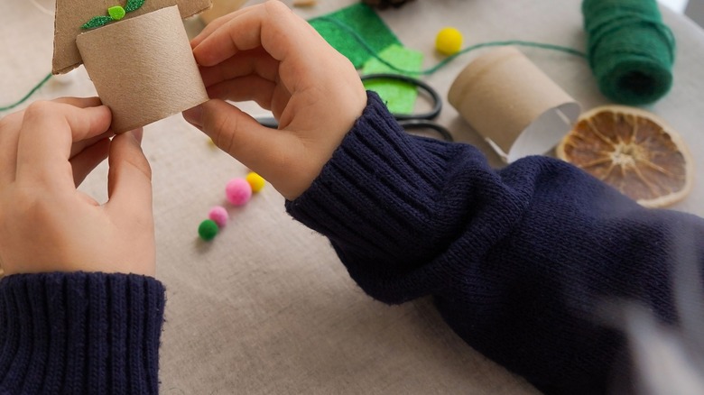 Hands crafting holiday decor from toilet paper tubes