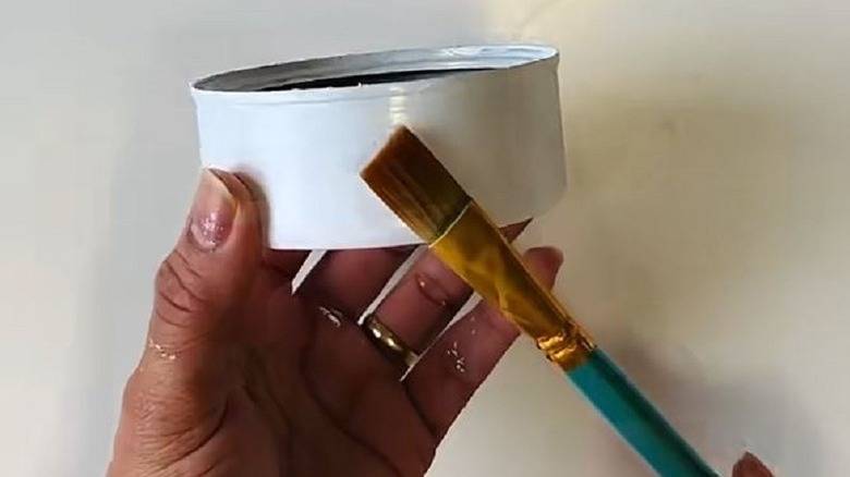 Hands holding painted tuna fish can for candle DIY