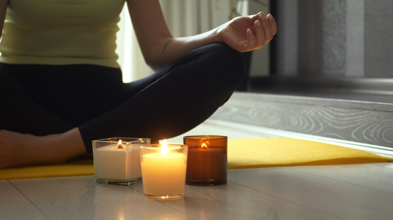 Woman meditating with candles on mat
