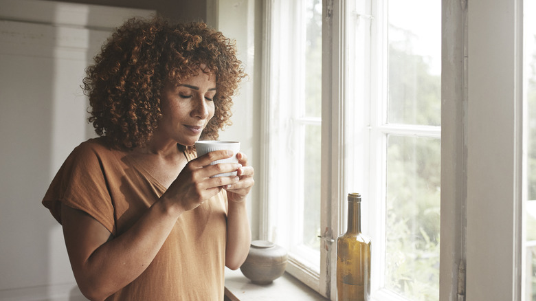 woman smelling coffee mug