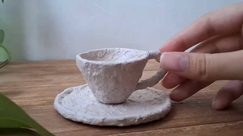 Person's hand holding DIY egg carton teacup decoration
