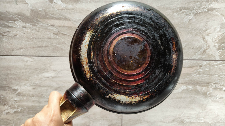 Person holding a worn old frying pan