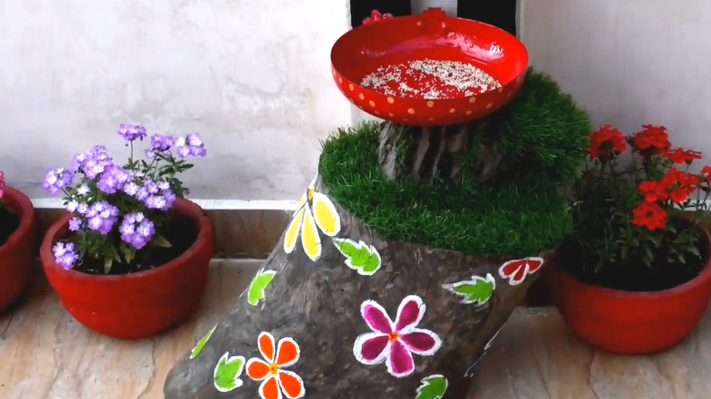 Painted skillet sitting on a trunk to create a bird feeder