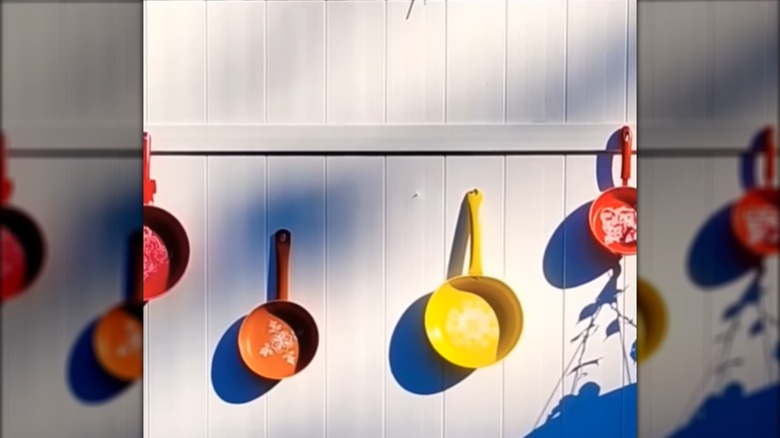 Frying pans spray painted in different colors with stenciled patterns on them