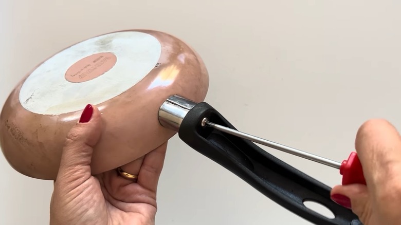 Person removing the handle of a frying pan