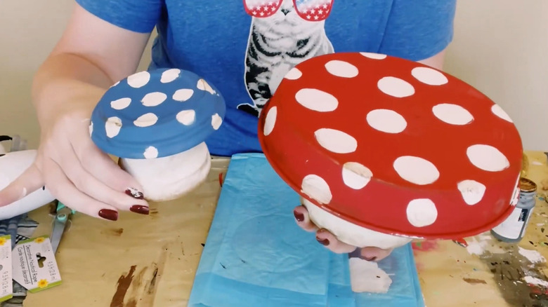 Creator holding up two DIY garden mushroom decorations
