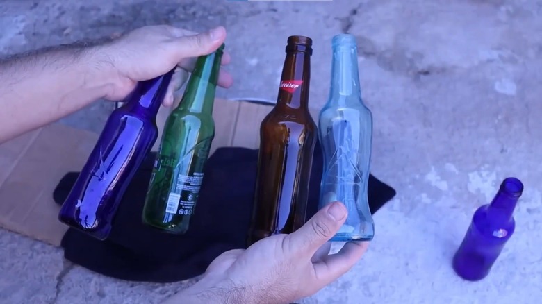 Person holding different colored glass bottles