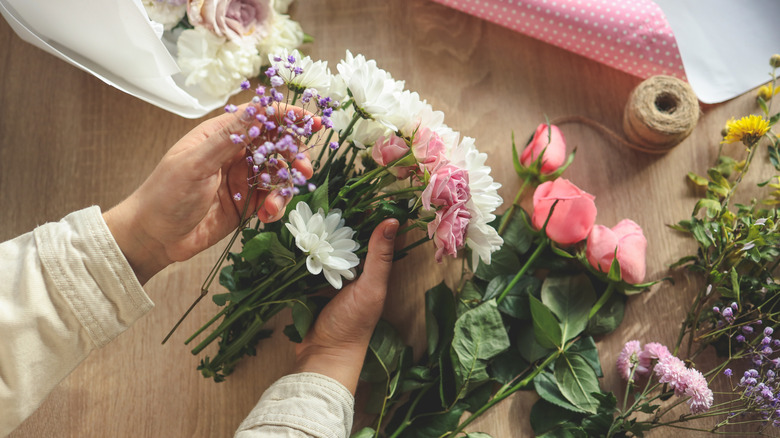 Closeup of a woman's hand arranging flowers on a table