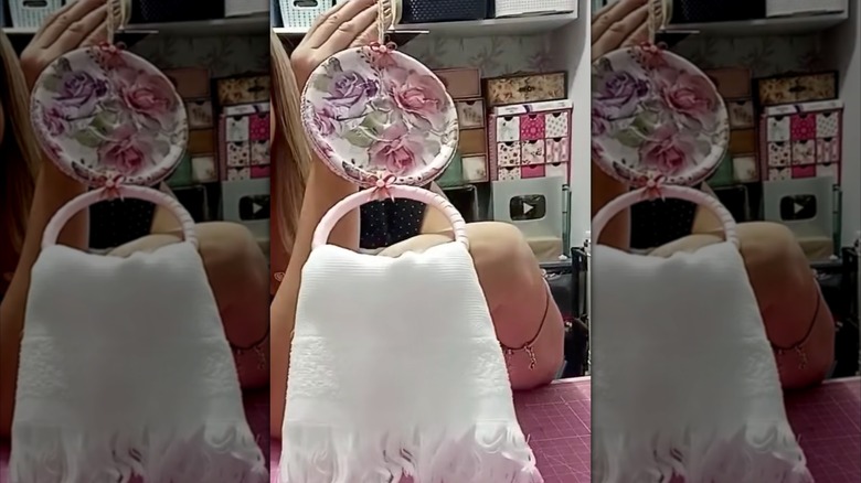 Hands holding a floral DIY towel hanger.