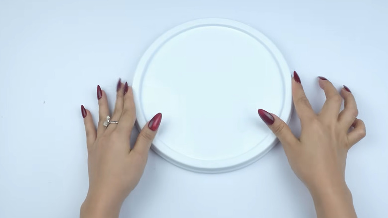 Hands holding a white plastic lid.