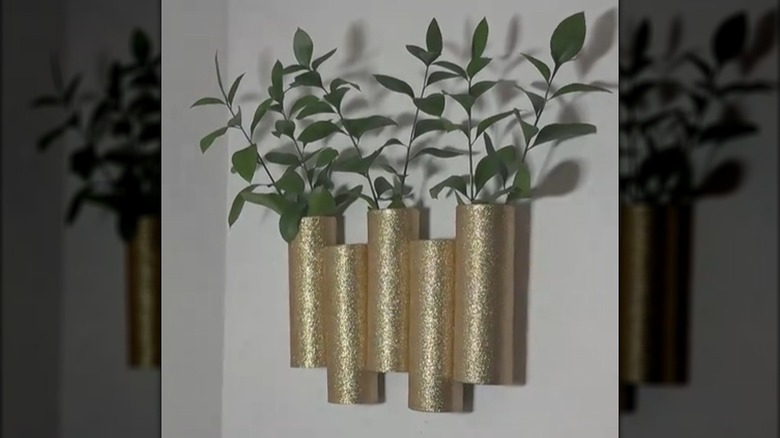 Hanging wall display made from Pringles cans with greenery inserted at the top