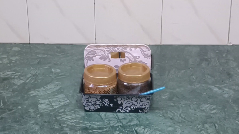 DIY organizer made from plastic takeout container with two jars inside