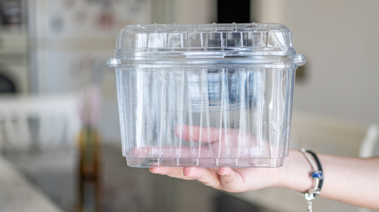 A hand holds an empty plastic container