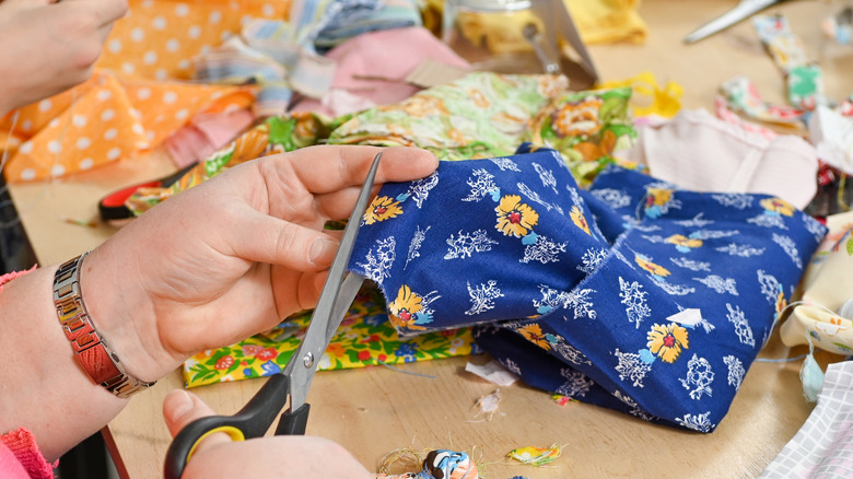 A person cuts scrap fabric with a pair of scissors
