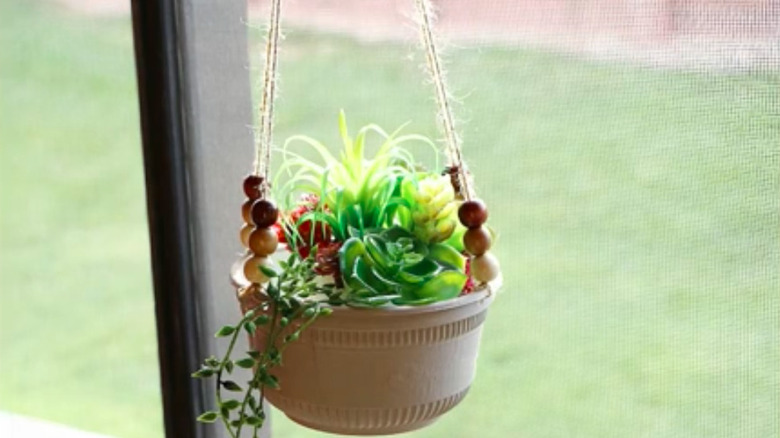 a hanging plant basket made from a repurposed plastic bowl