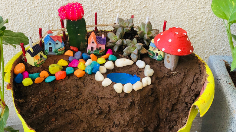 Colorful fairy garden made with a broken plastic bucket