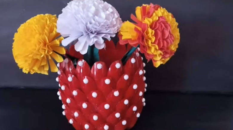 A plant holder made from a plastic container and spoons