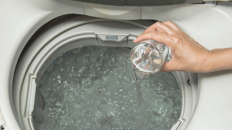 Hand pouring clear liquid in a wash