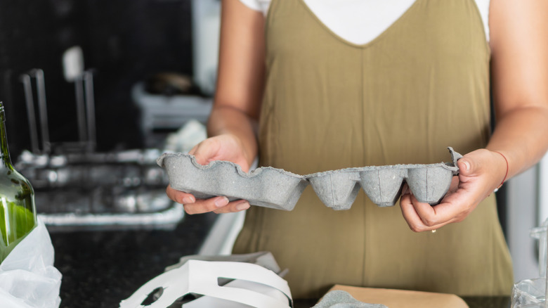 Woman holding an empty paper egg carton.
