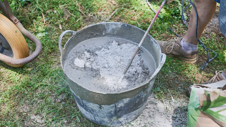 A person mixing concrete in a bucket