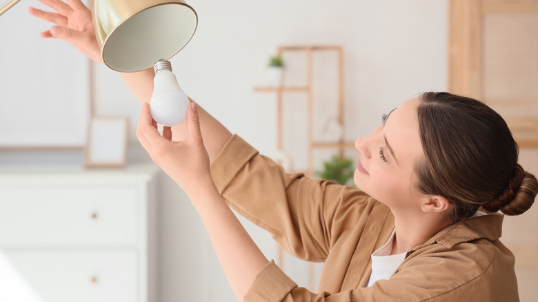 Woman removing old lightbulb from lamp