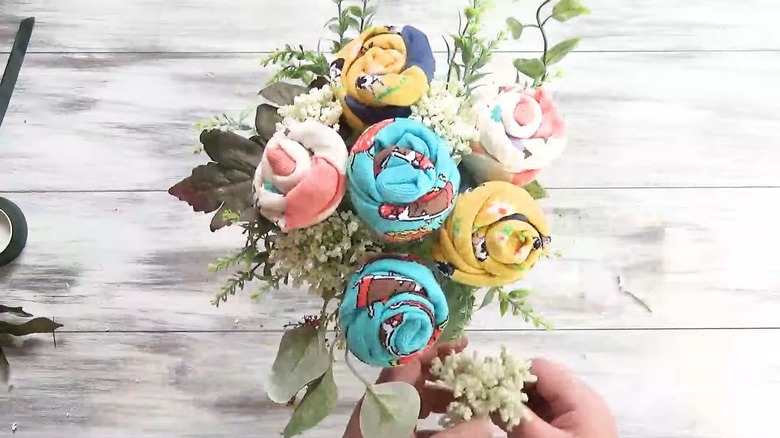 A colorful floral arrangement featuring sock-made flowers and a few fillers