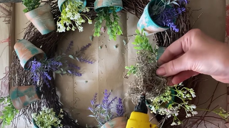 Person making DIY wreath out of nursery plant pots