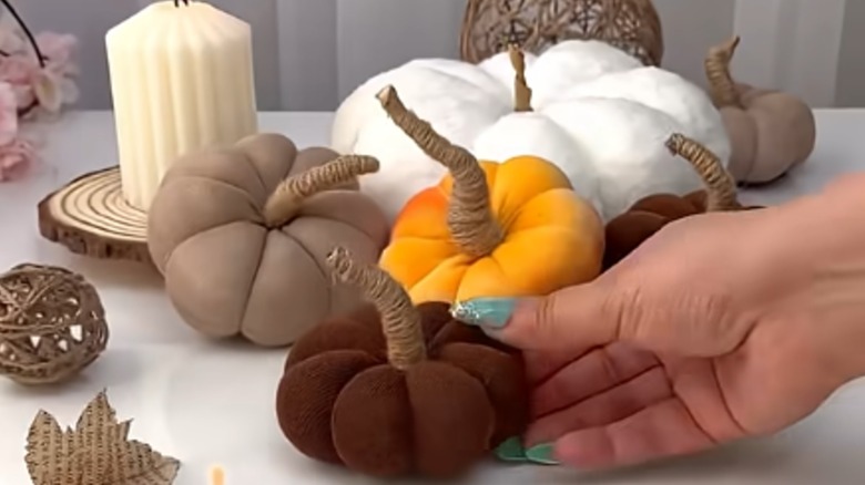 A blogger sets a homemade sock pumpkin in front of a group of other pumpkins.