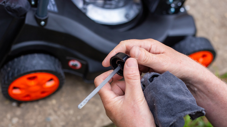 Person checking the oil in a lawn mower