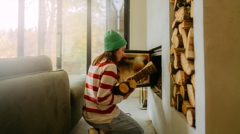 woman adding another log to her fireplace