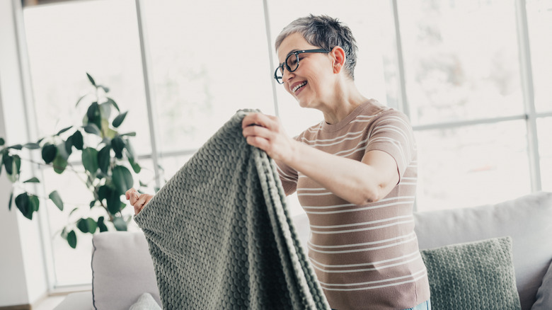 Woman folding a gray blanket in a living room