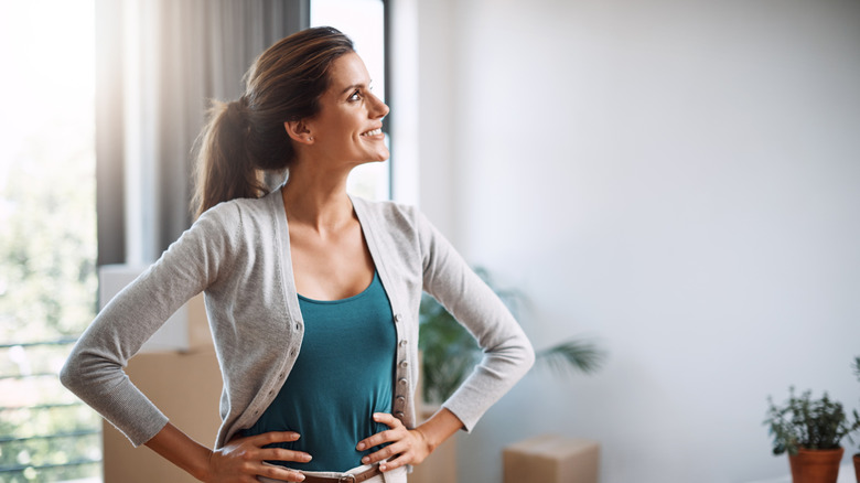 A woman looks at a white wall in a house