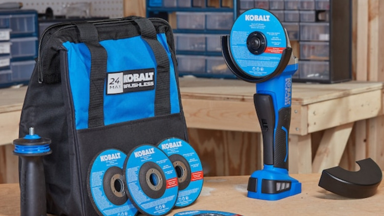 A Kobalt Cordless Angle Grinder on a table with a bag and replacement discs