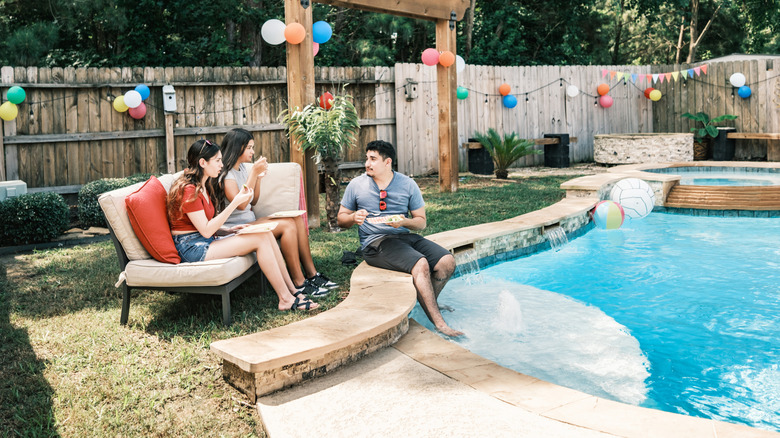 A group of friends celebrate by a backyard pool