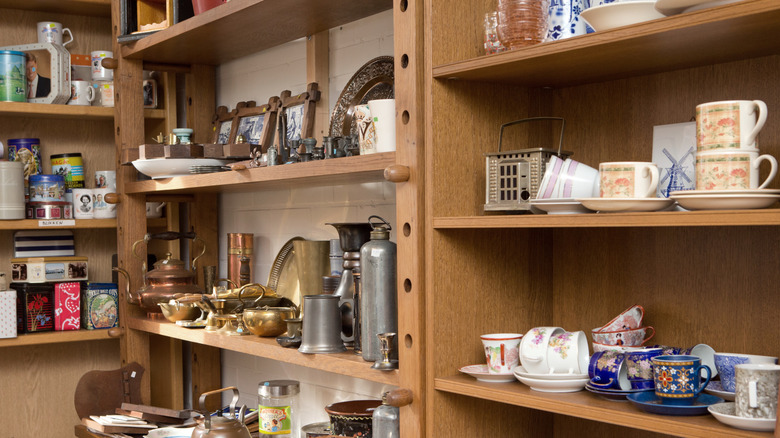 Wooden shelves stocked with kitchenware items in a thrift store.