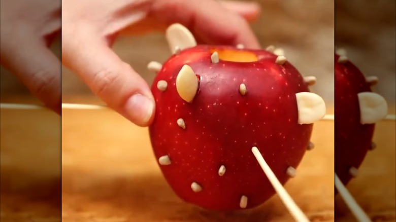 A DIY apple feeder dotted with various seeds.