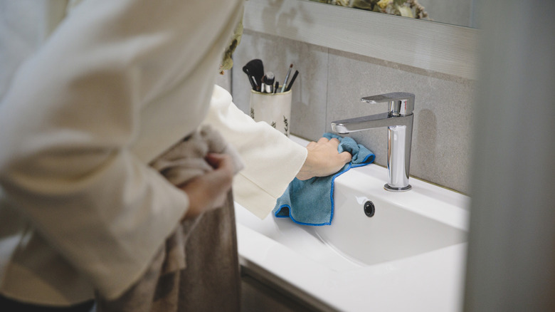 woman wiping down sink faucet