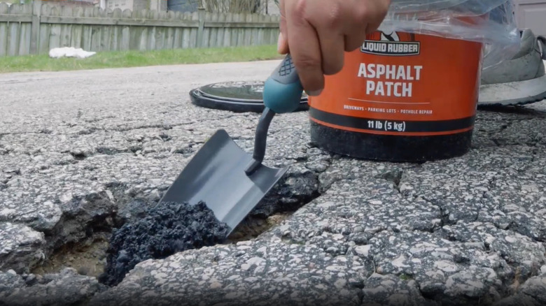 Putting cold patch asphalt repair product into a driveway pothole