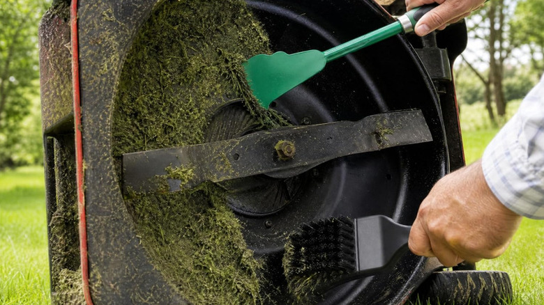 Using a scraper and a brush to clean away stuck grass