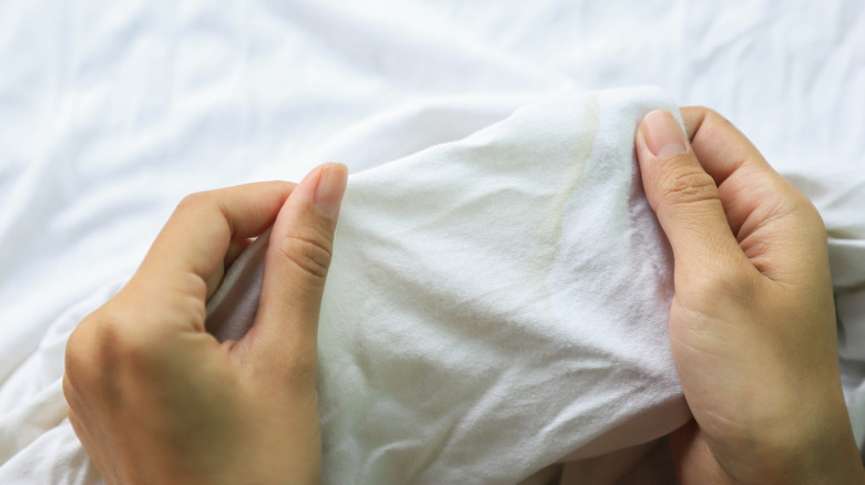 Close up of yellow faded sweat stain on white sheets