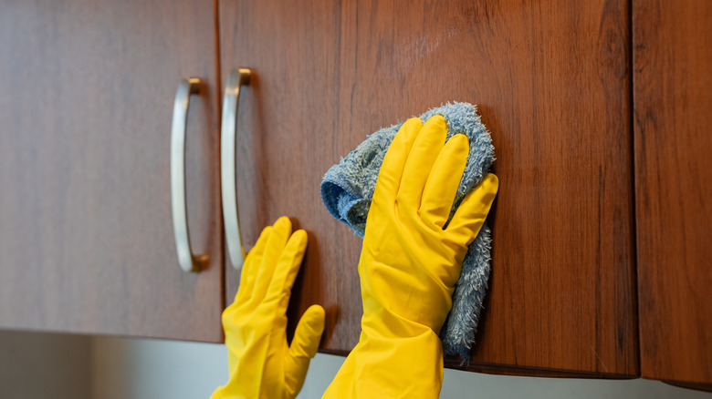 A person cleaning wood cabinets