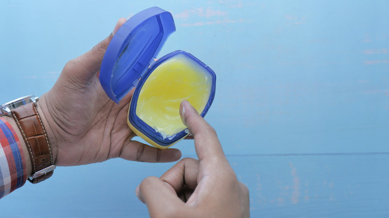 Man dips finger into petroleum jelly