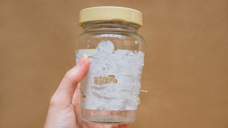 Hand holding a jar with leftover sticker residue