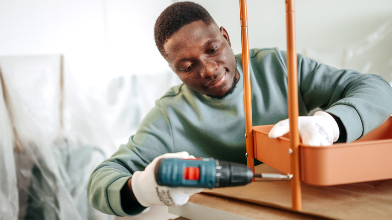 A person using a drill with a screwdriver attached