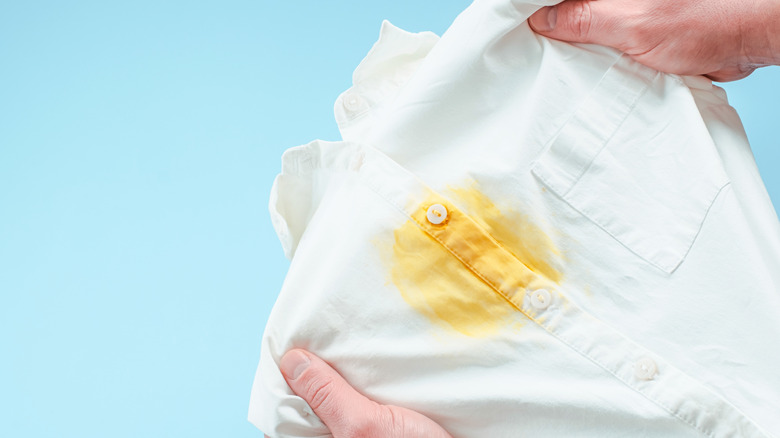person holding a white shirt with yellow stain
