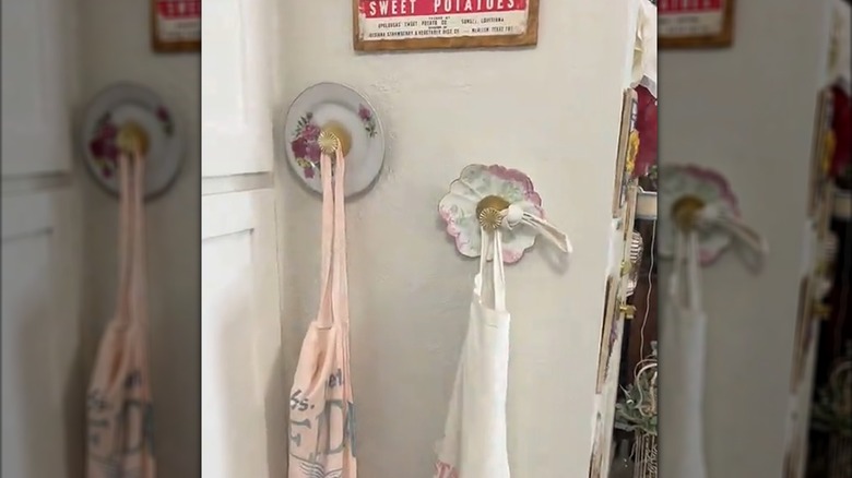 Two wall hooks made from decorative vintage plates with aprons hanging on them