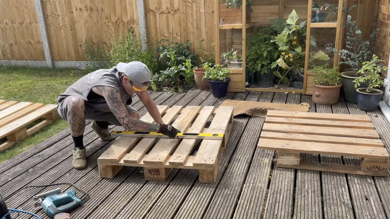 A person measuring wood pallet outside