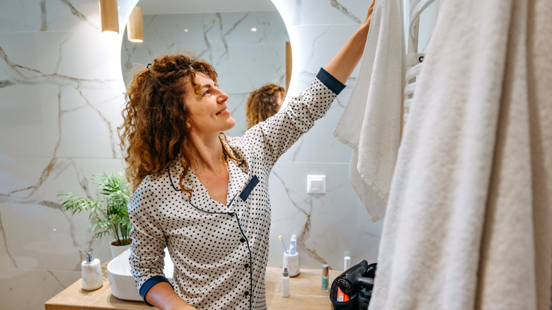 Woman reaching for towels in bathroom