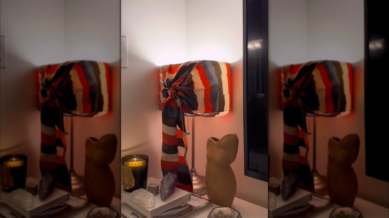 A table lamp with a colorful striped silk scarf tied around the shade