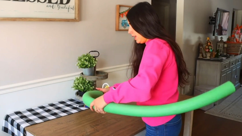 A woman shapes a green pool noodle for a DIY